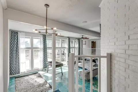 View from the white-railed landing over the window-lined game lounge with indoor rock garden and turquoise stained-concrete floor at Brompton Manor, Oklahoma City