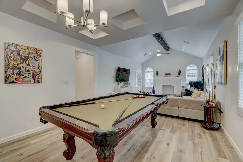Bright game room with billiards table, vaulted ceiling, sectional sofa and wall-mounted TV at Quail Creek Manor, Oklahoma City
